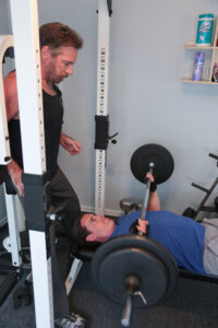 personal trainer spotting client on bench press